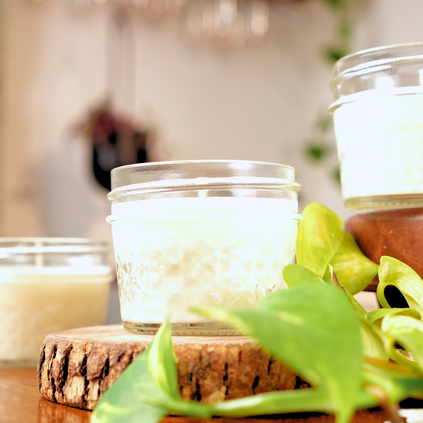 Candle in a glass jar on a wooden block with a blurred background