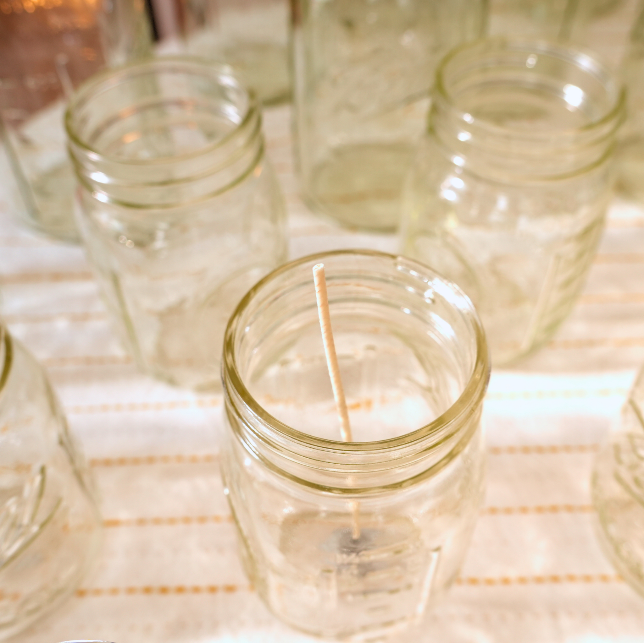 Clear glass jars with wicks on a white surface