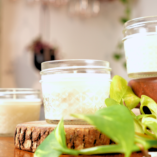 Candle in a glass jar on a wooden block with a blurred background